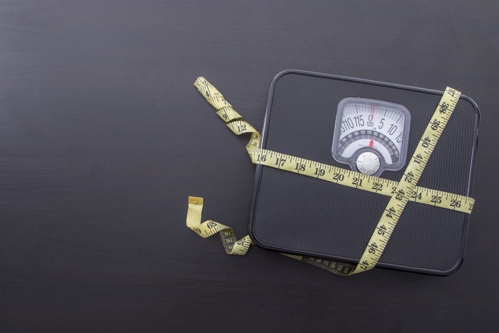 measuring tape around a weighing scale