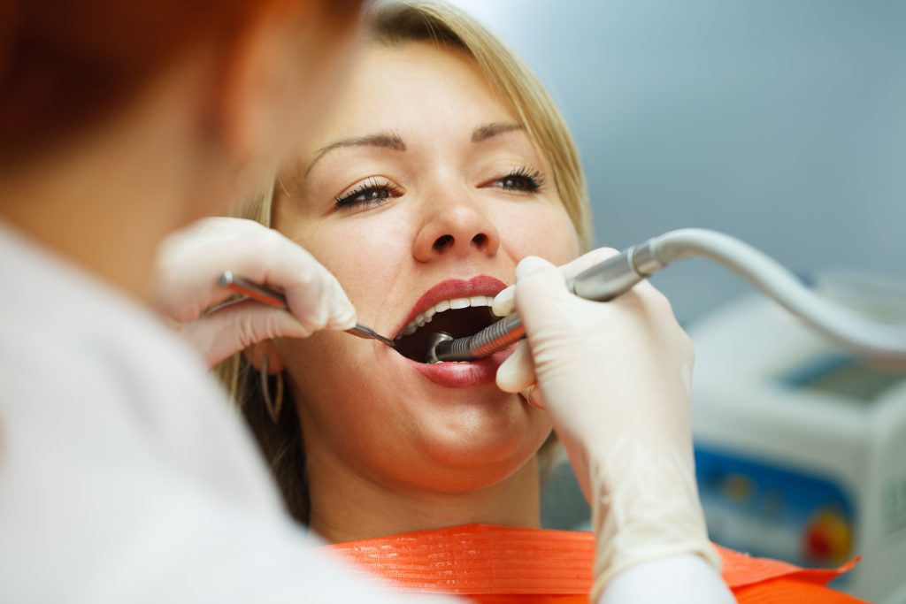 a woman getting her teeth checked by a dentist