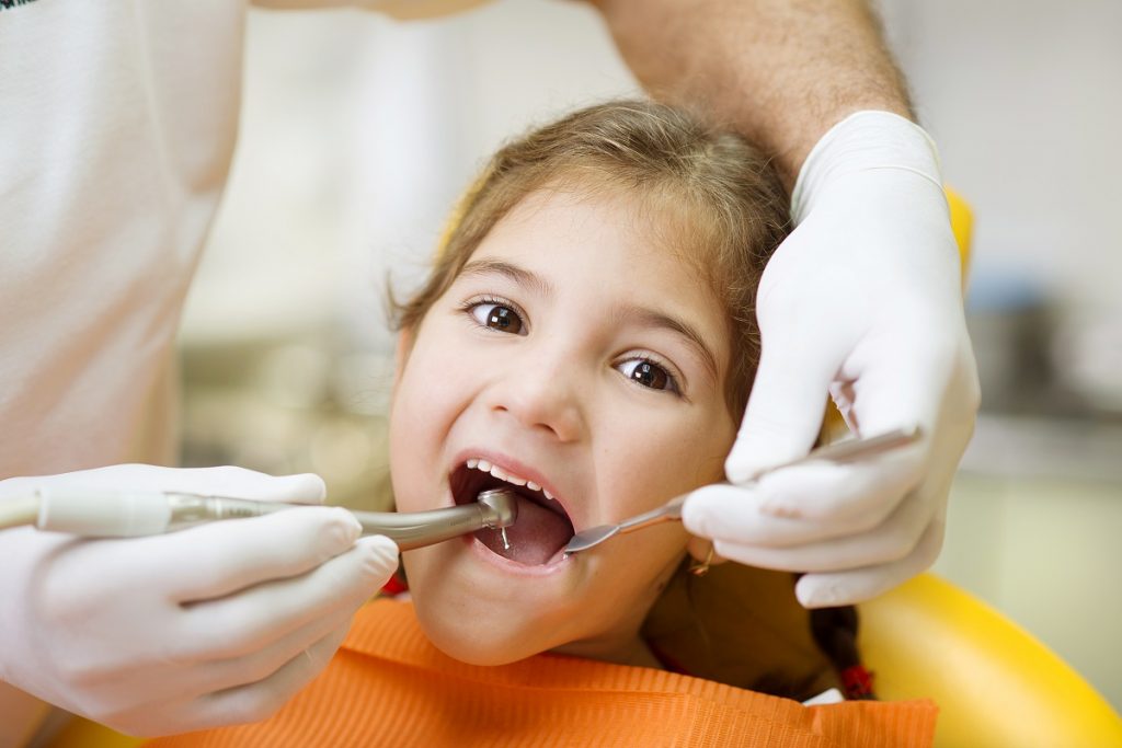 Dentist checking child patient's teeth
