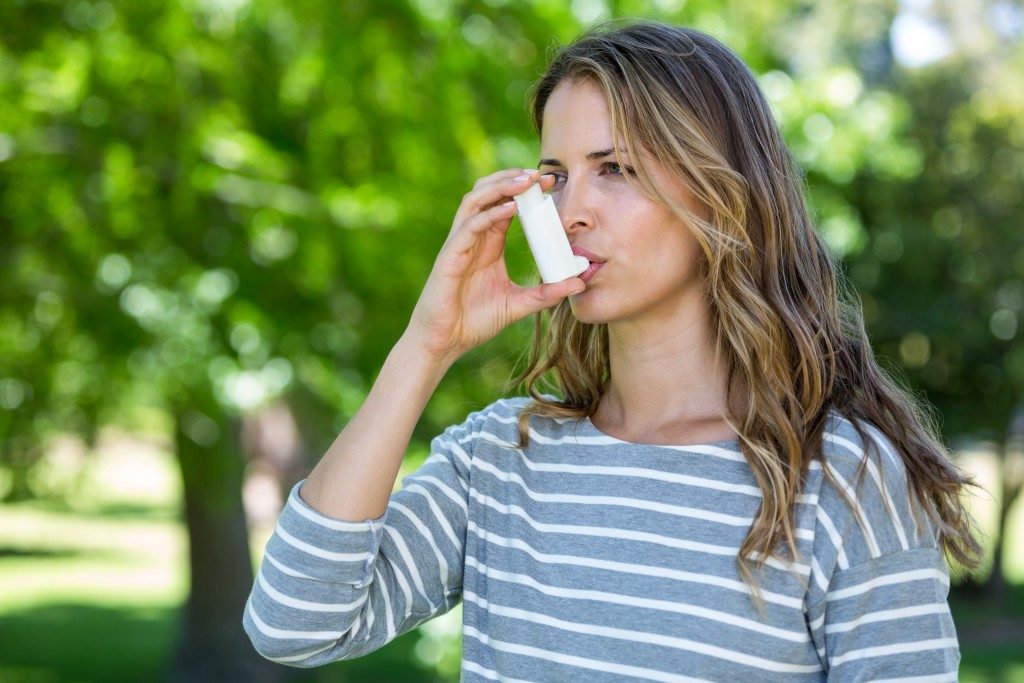 Woman using inhaler at the park