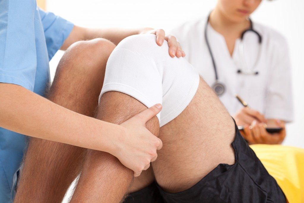 doctor supervising healing of patient after knee surgery