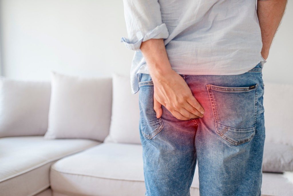 man holding his bottom part due to hemorrhoids