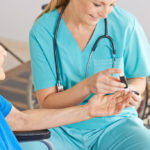 Geratric nurse monitoring blood sugar of senior woman with diabetes