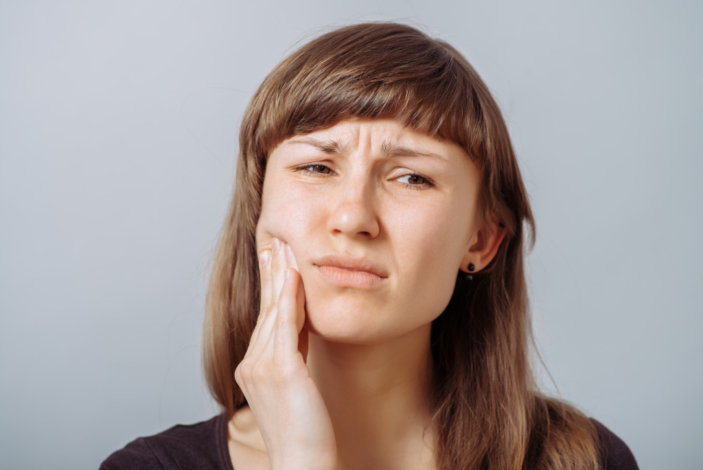 A woman holding her cheek because she is in pain from a cavity