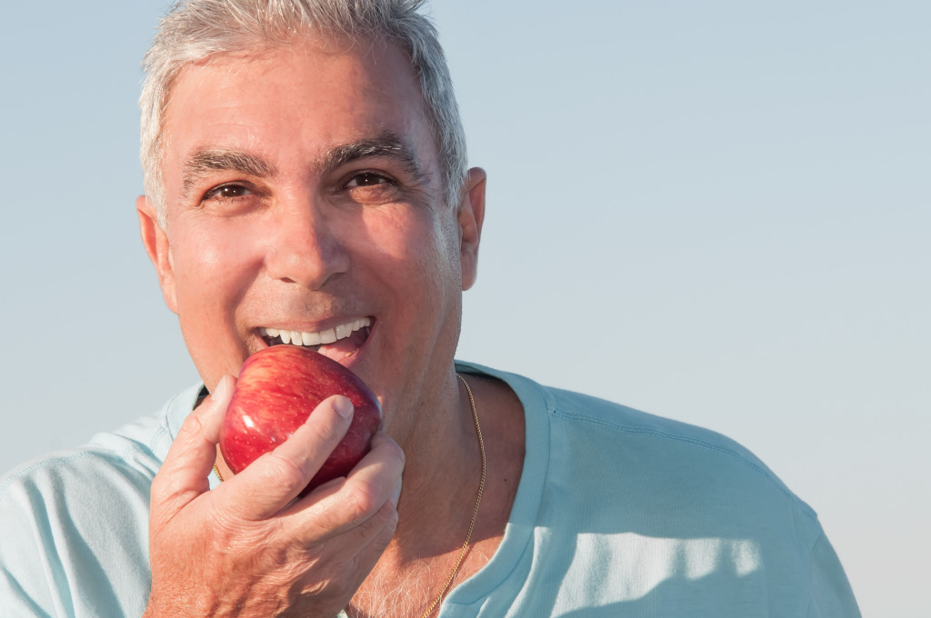 Senior eating apple with healthy teeth