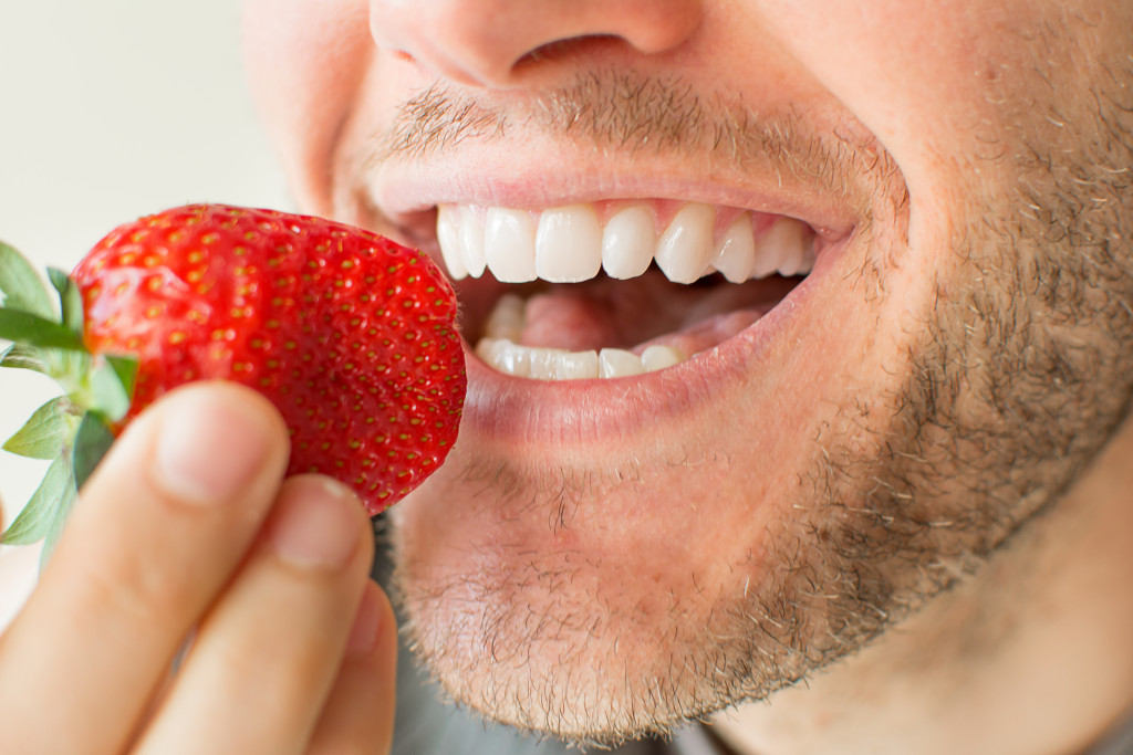 A closeup shot of a man eating a strawberry