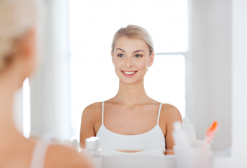 young beautiful woman smiling at her reflection