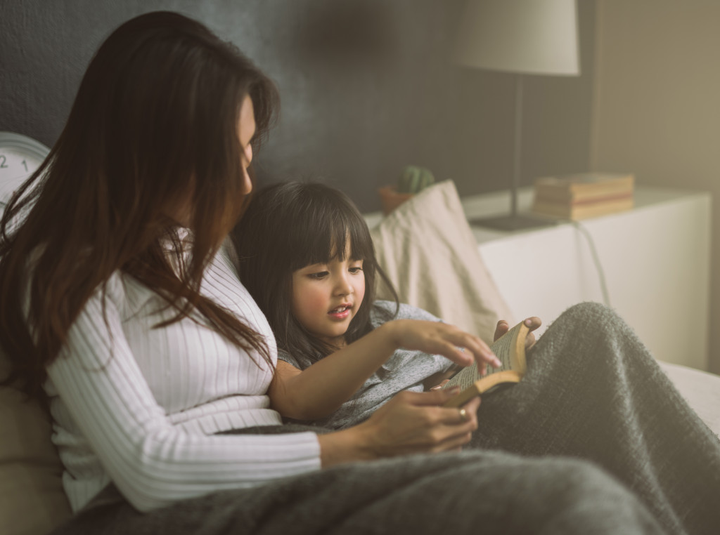 mother reading daughter a book before bed